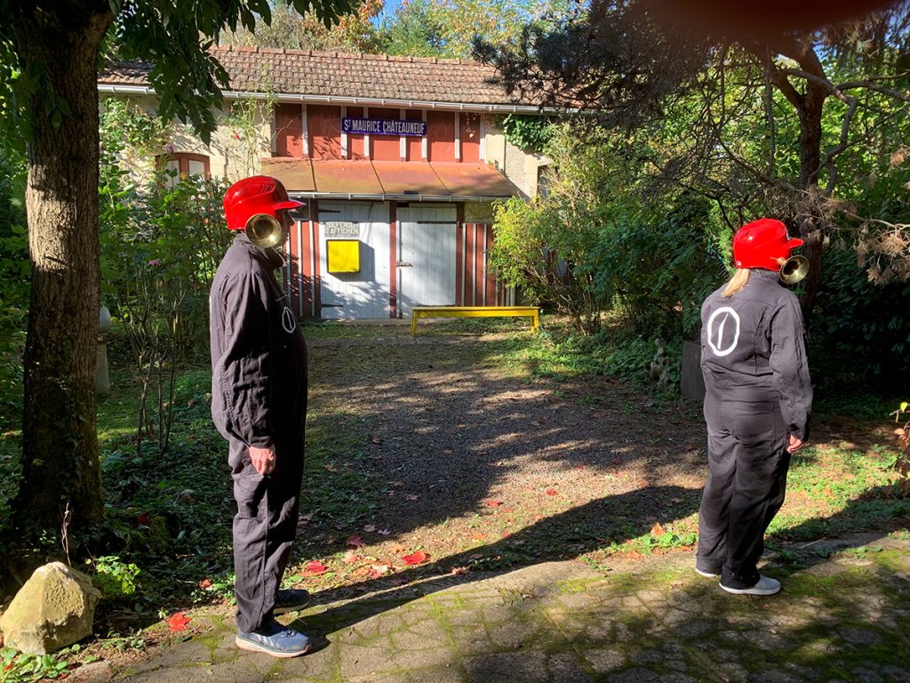 2 personnes en costume gris avec casques rouges train de performer dans le jardin