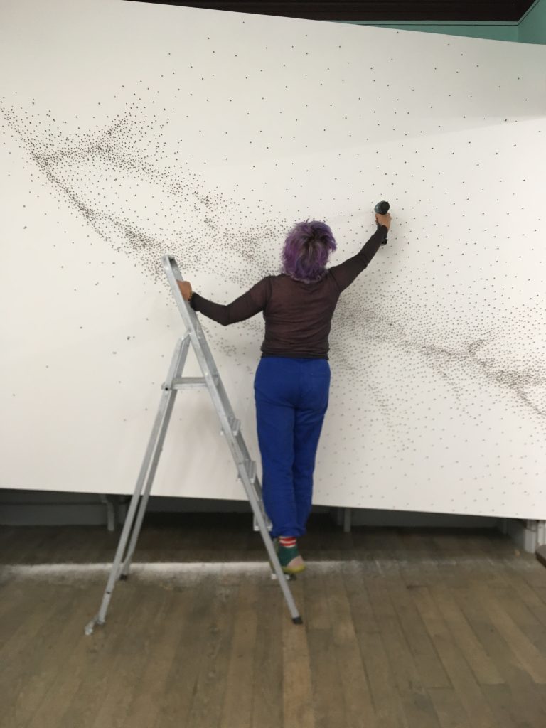 L'artiste en train de monter sa pièce La migration des étoiles, composée de milliers de clous de girofles