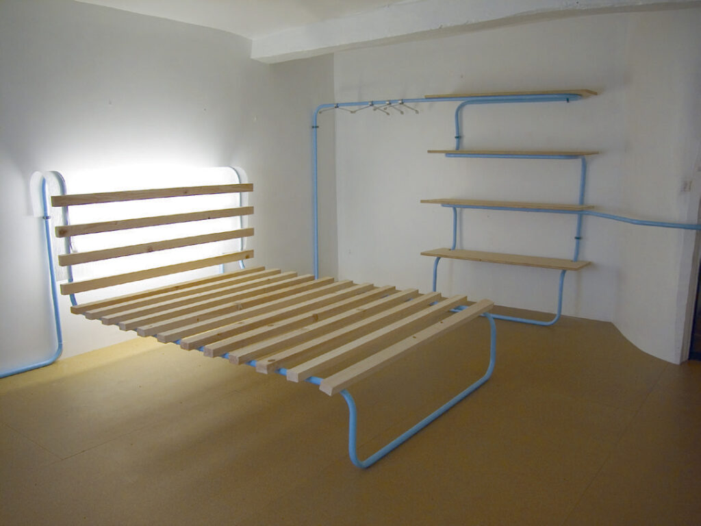 Chambre créée par le designeur, en bois clair et tuyaux bleu clair