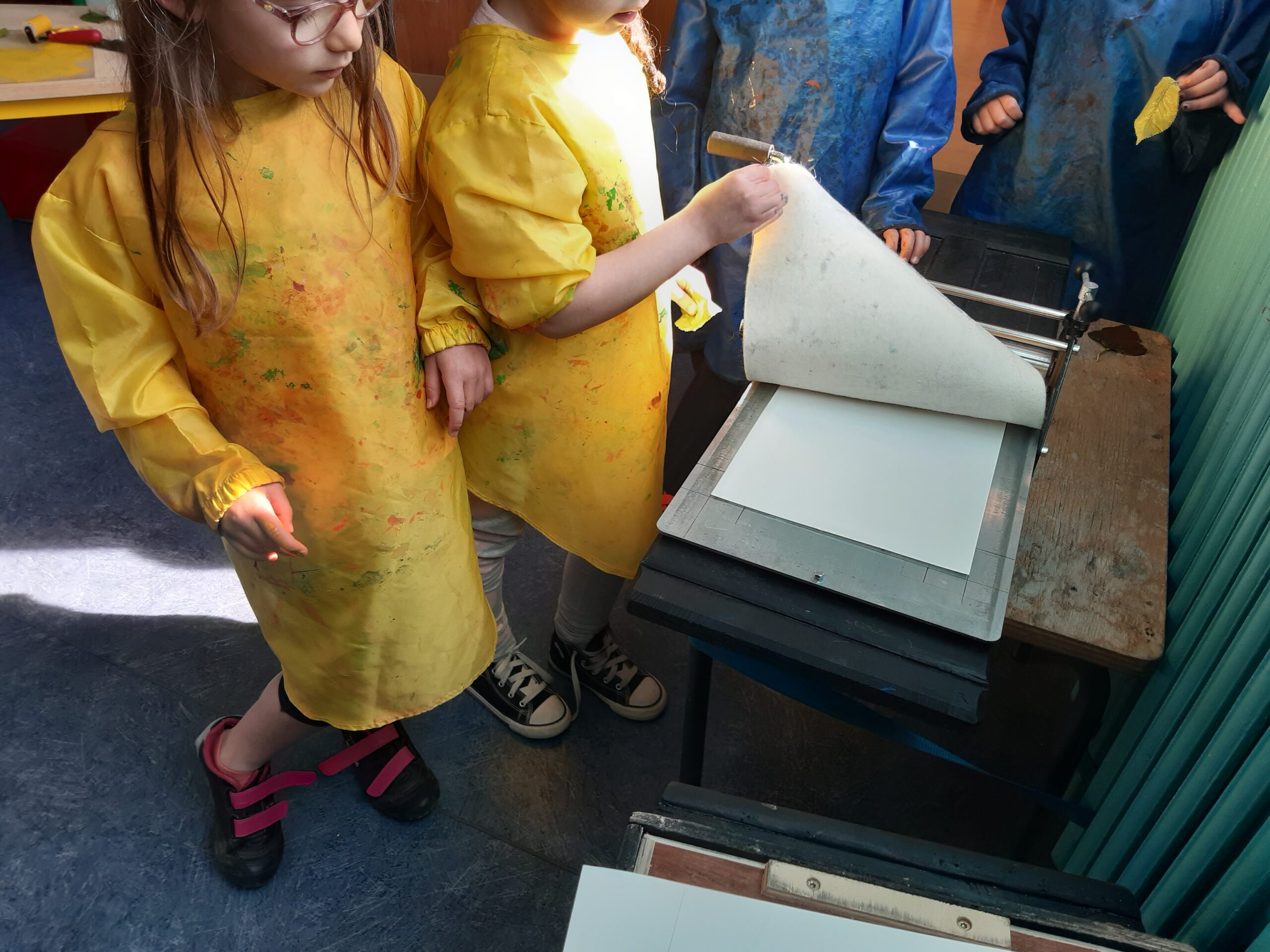 Deux élèves en tablier taché d'encre tournent les pages d'un livre.