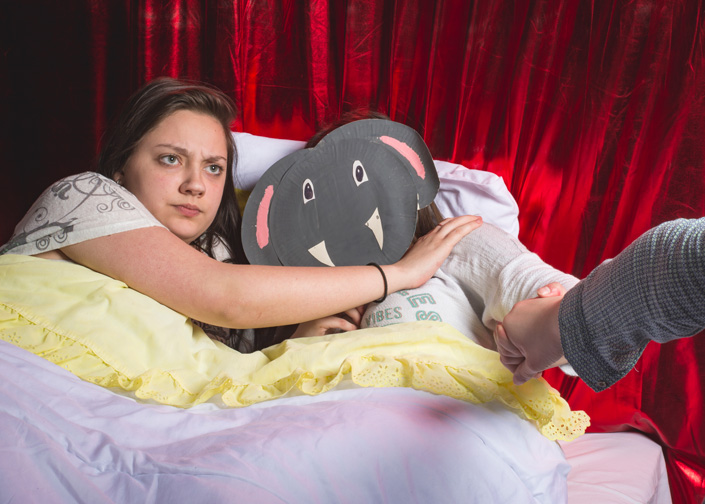 Une élève au lit avec une grosse peluche grise.