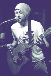 Stuart o'Connor en train de jouer de la guitare