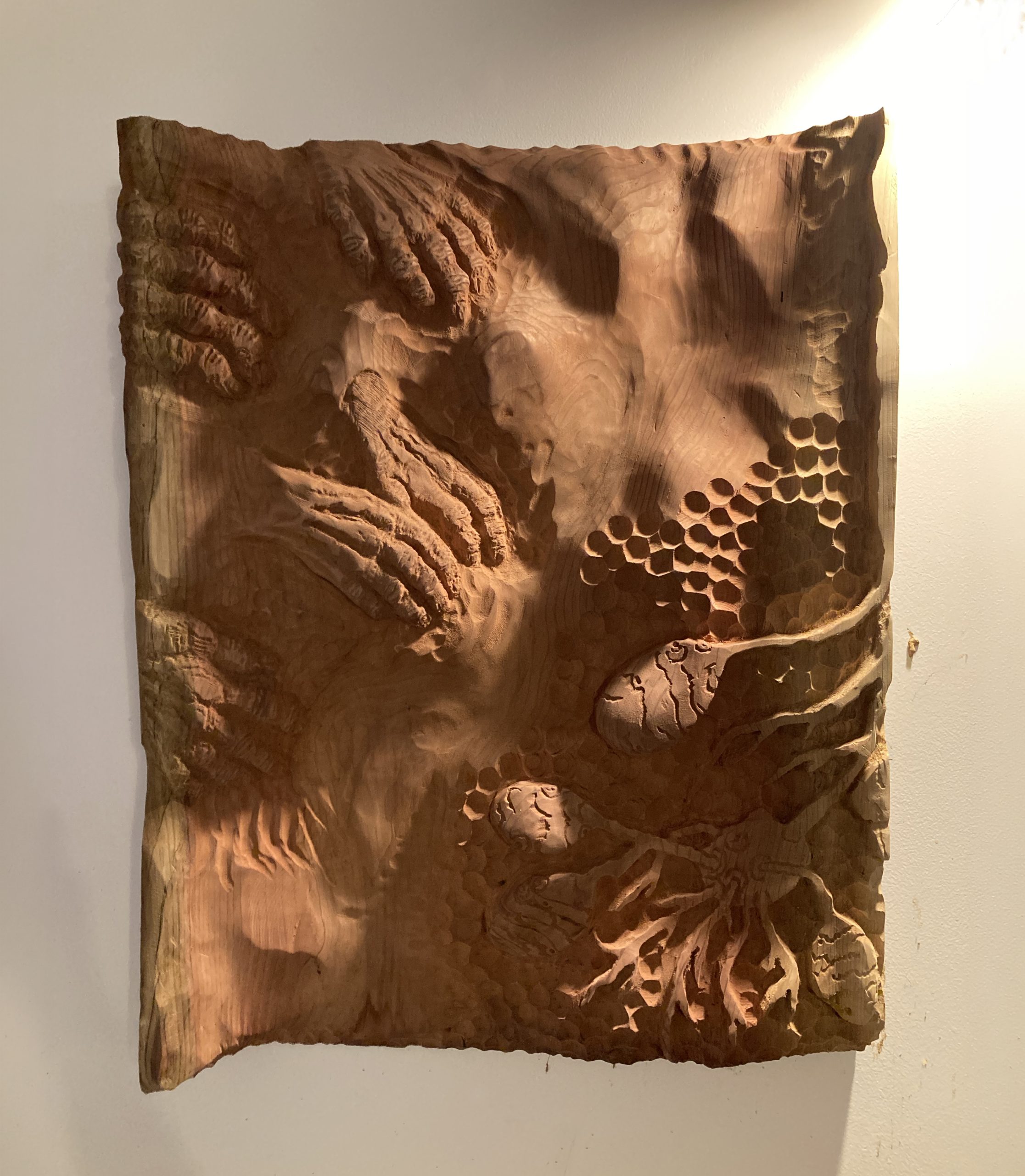 stelle en bois sculptée qui montre des mains en train de creuser la terre pour atteindre des tubercules