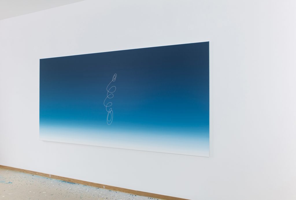 Peinture intitulée Superstring. Un long format paysage peinte en dégradé de bleu vers le blanc. Au centre un dessin d'une fine volute blanche.